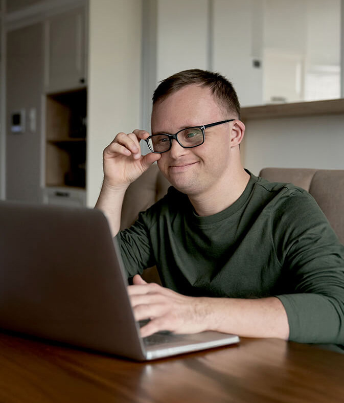 Cheerful adult man with down syndrome using a laptop